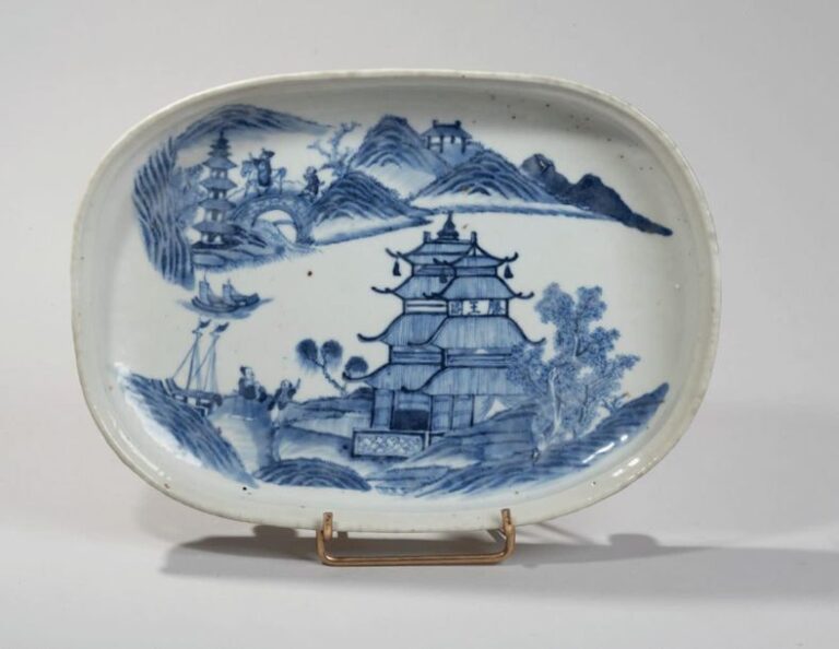 Plat ovale en porcelaine à décor en bleu sous couverte de pagodes et bateaux dans un paysage lacustr