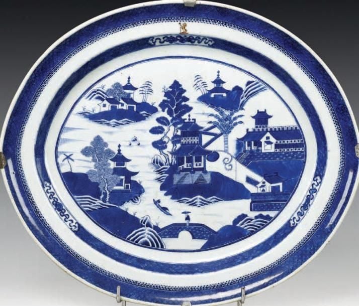 Plat ovale en porcelaine orné en bleu sous couverte d'un paysage lacustre animé de pagodes, pavillons et embarcation