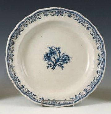 Plat rond à bord contourné, décor polychrome de fleurs au centre et de dentelles sur le bor