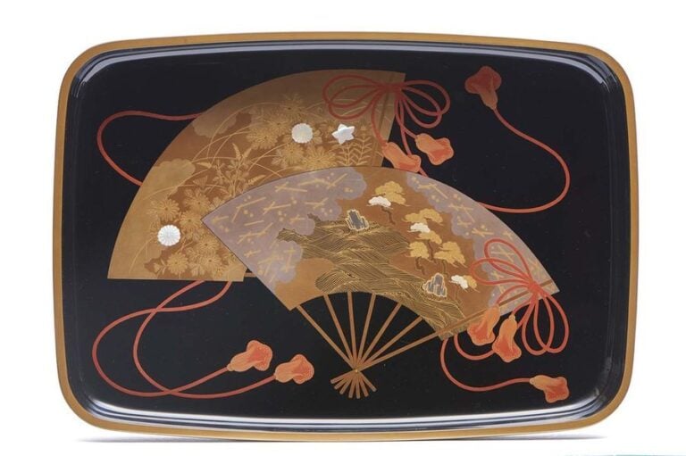 Plateau laqué noir à coins arrondis (hirobuta) décoré de deux éventails pliants garnis de cordelettes rouges et à décor respectivement de pins sur une plage et de chrysanthèmes en laque maki-e rouge et doré