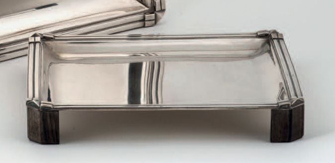 PLATEAU RECTANGULAIRE en argent, la bordure à double cannelure terminée par un motif géométrique, angles pincés à pans coupés; il repose sur quatre petits pieds en ébène de Macassa