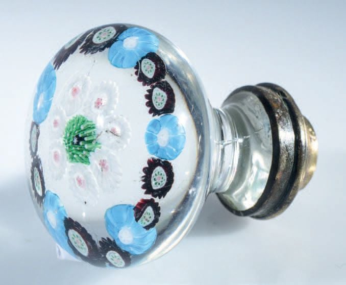 Poignée de porte ornée de deux cercles concentriques, l'un formé de cinq bonbons bleu clair et dix bonbons violets, le second de sept bonbons blancs autour d'un bonbon central vert (fêlure à la base