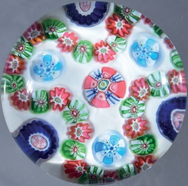 Presse-papiers à fond blanc opaque orné d'une guirlande trilobée composée de bonbons verts et blancs alternés de bonbons roses et blancs, contournant trois bonbons bleu cobalt, blancs et roses, trois bonbons bleu clair et blancs et un bonbon central complexe rose, blanc, vert et ble