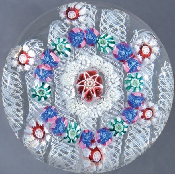Presse-papiers à fond composé de sept torsades blanches filigranées, orné d'un cercle de six bonbons blancs et roses, d'un cercle de douze roses roses et bleues et de six bonbons verts et blancs, d'un cercle central de bonbons blancs étoilés entourant un bonbon en étoile rouge et blan