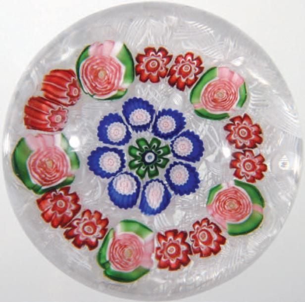Presse-papiers à fond de torsades blanches filigranées orné de deux cercles, l'un composé de cinq roses de Clichy vertes et roses et de dix bonbons rouges et blancs, le second de huit bonbons bleus, blancs et roses, autour d'un bonbon ver