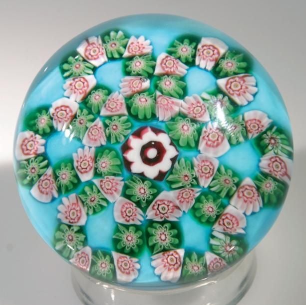 Presse-papiers à fond turquoise orné d'une rosace formée d'une guirlande à six boucles formée de bonbons verts alternés de bonbons blancs et roses autour d'un bonbon central blanc et rose (fêlure de rétraction