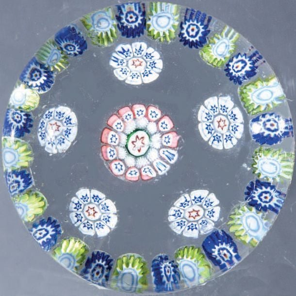 Presse-papiers à motif de couronne de bonbons jaunes et blancs alternés de bonbons bleus et blancs, entourant cinq bonbons tricolores à étoiles et un bonbon central complexe rose, blanc, bleu et ver