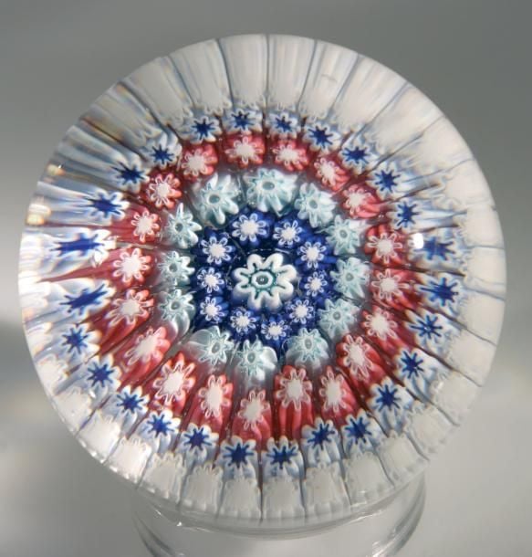 Presse-papiers à talon orné de cinq cercles concentriques de bonbons bleus et blancs et de bonbons roses et blancs autour d'un bonbon central blanc et ver