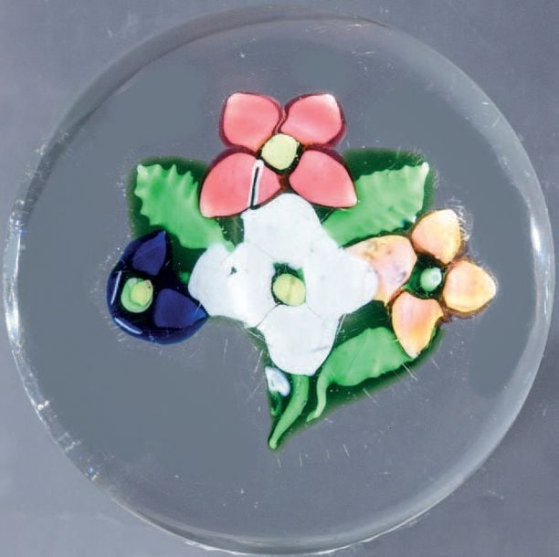 Presse-papiers orné d'un bouquet composé d'une fleurette blanche, de deux fleurettes roses et d'un bouton bleu, sur une tige verte à trois feuille