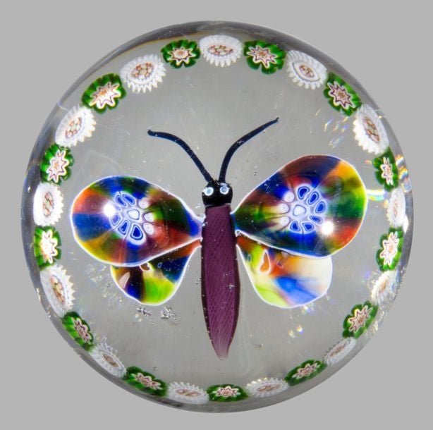 Presse-papiers orné d'un papillon à corps violet et ailles polychromes entouré d'une couronne périphérique de bonbons polychromes alterné