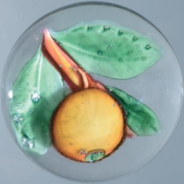Presse-papiers orné d'une pomme orangée, sur une tige ocre portant trois feuilles vert tilleu