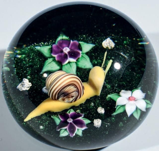 Presse-papiers signé et daté B 1977, à fond vert imitant un sol naturel orné d'un escargot et de trois fleurs (deux violettes et une blanche