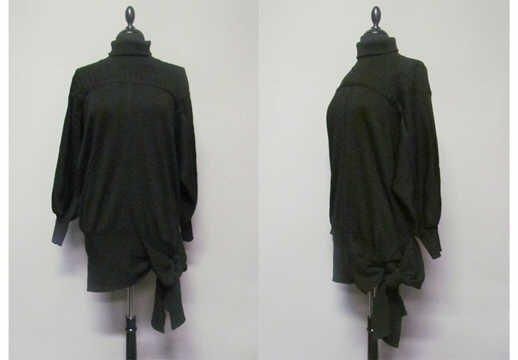 PULL-OVER tunique de forme entravée en laine fantaisie noire, col montant, poignets et taille basse en bord-côtes, cette dernière se transformant en pans à nouer sur le côté gauche (griffe blanche, graphisme or) (env TM)