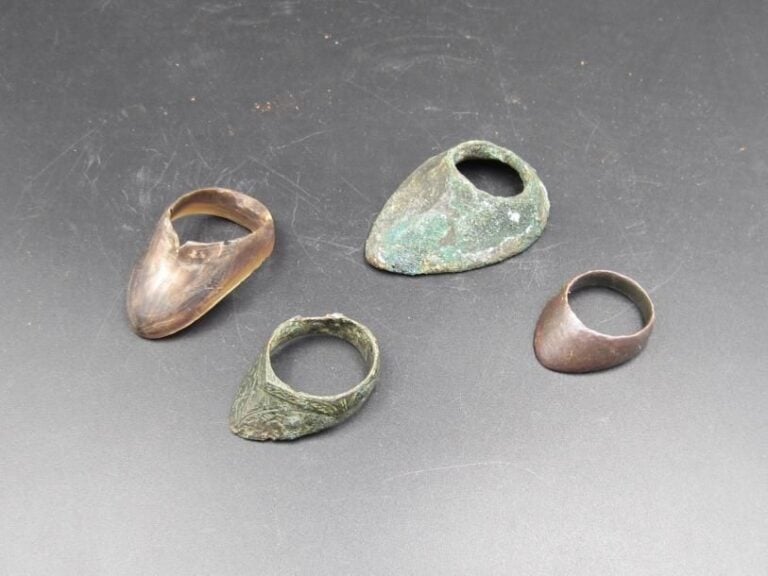 Quatre bagues d’archer  Époque Médiévale et postérieure  Largeur de la plus grande : 5,2 cm  Trois en bronze à patine de fouille, dont l’une à décor gravé et une en corn