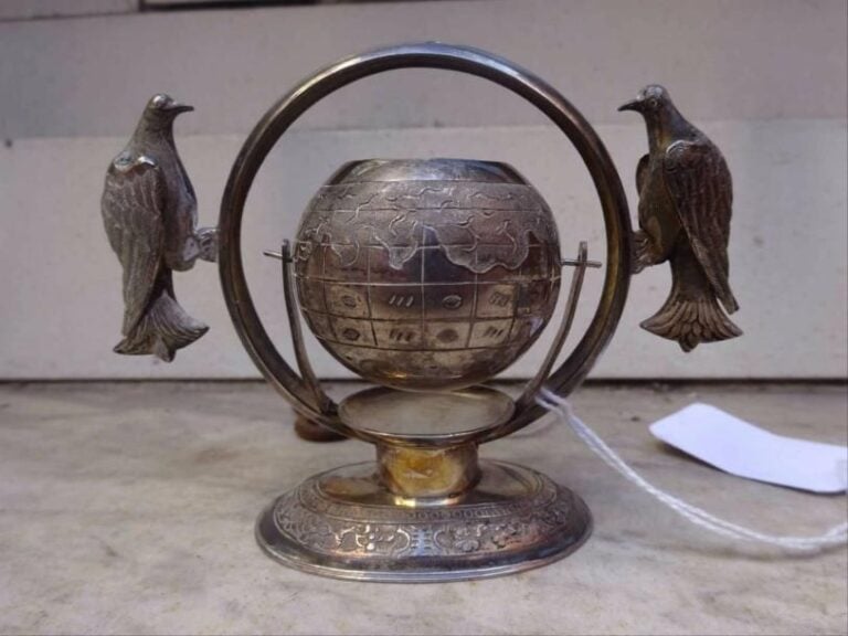 REPOSE-SACHET DE THE EN ARGENT Vietnam, Epoque XXe siècle Formant cercle sur piédouche, centrée d'une sphère pivotant sur un axe et flanquée de deux oiseaux affronté
