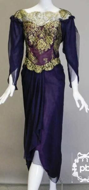ROBE composée d'un corsage en tulle rebrodé de fils métallisés dorés figurant un motif floral et d'une jupe portefeuille drapée en mousseline crépon bleu nuit, manches longues à l'identique soulignées de ruchés, décolleté bateau et taille festonnés (T14 uk)