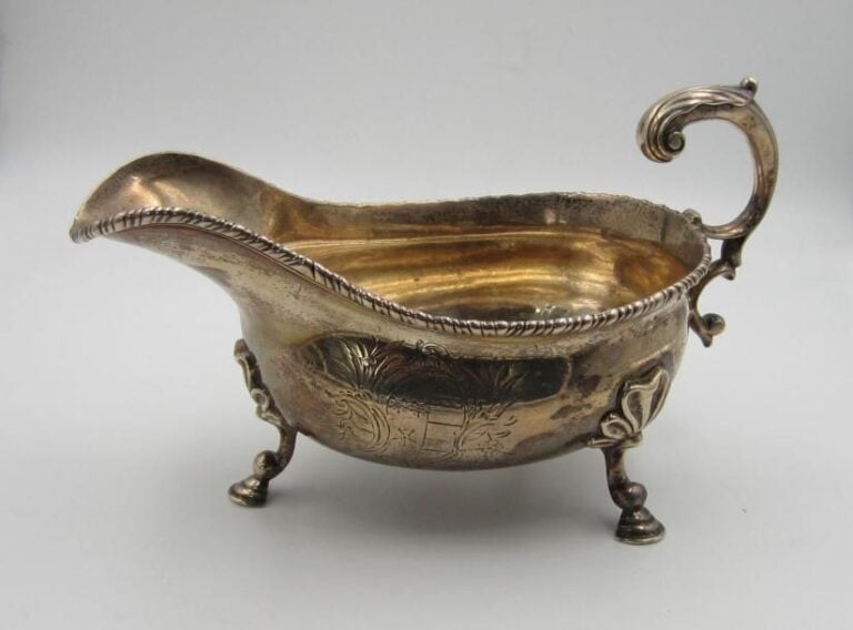 Saucière tripode en argent de forme casque, la bordure à torsade; le corps gravé d'armoirie