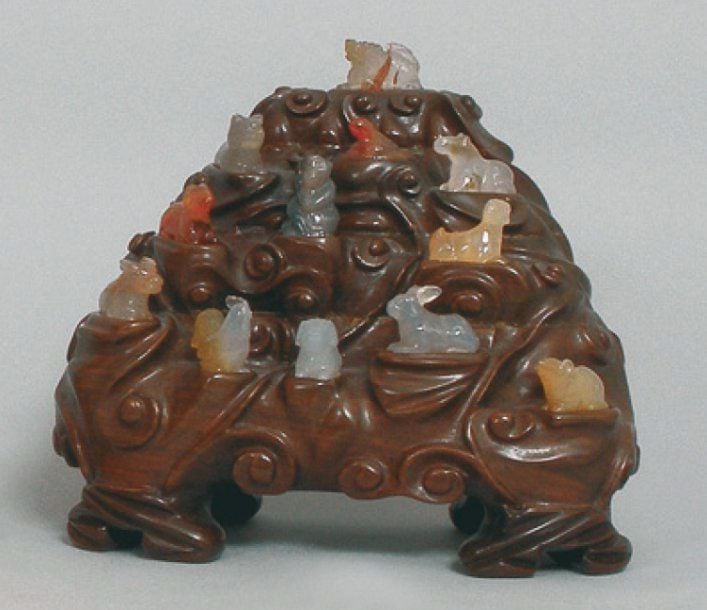 SCULPTURE en bois représentant un rocher sur lequel sont disposés les douze animaux du zodiaque en agate et cornalin