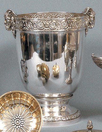 Seau à champagne en argent posant sur un piédouche à feuilles de laurier et godrons, la bordure ornée d'une frise de fleurs et entrelacs, les prises figurant des têtes de bélier