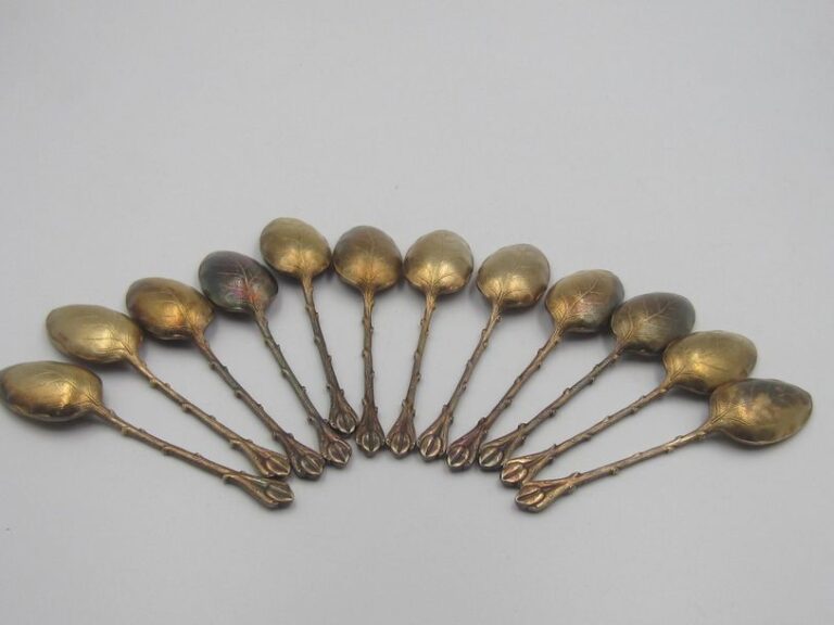 Série de 12 cuillères à moka en métal doré, le cuilleron figurant une feuille nervurée, la spatule grain de caf