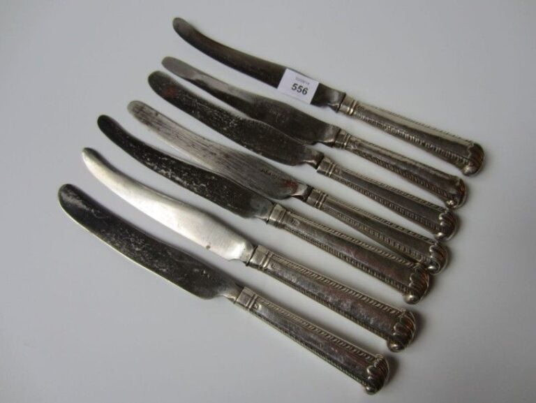 SÉRIE DE SEPT COUTEAUX, les manches en argent à bordures de petits rinceaux et terminés par une agrafe feuillagée en cross