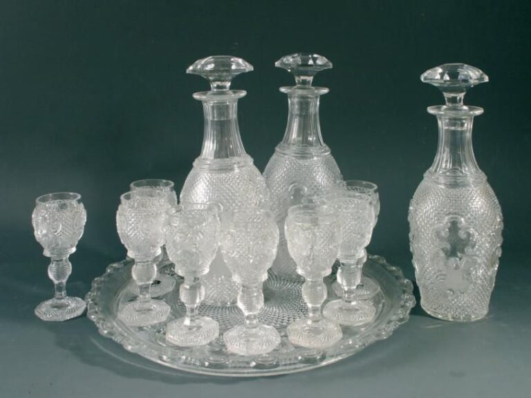 Service à liqueur comprenant huit verres à pied, trois flacons et un plateau en cristal moulé pressé à motif de rinceaux sur fond diamanté et perl