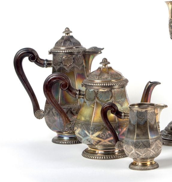 Service à thé café en argent uni (950 millièmes) à pans, à décor amati de coquilles et fleurettes dans sa partie basse, sur une base godronnée, comprenant une cafetière, une théière et un pot à lait ; prises en bois bru
