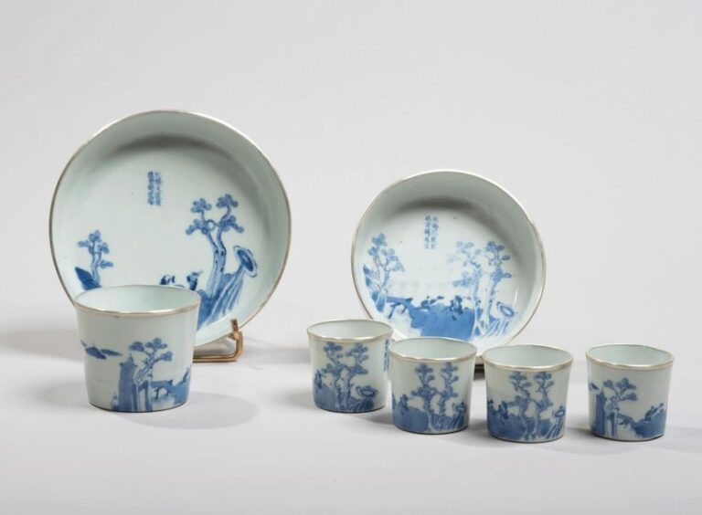 Service à thé comprenant cinq sorbets et deux coupelles en porcelaine décorée en bleu sous couverte de lettrés près d'un pont et poème