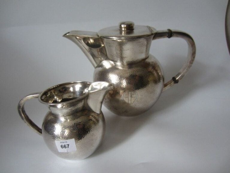 SERVICE DEUX PIÈCES en argent martelé comprenant théière et pot à lait; la panse monogrammée AA Travail américain, 995? Poids: 980 g