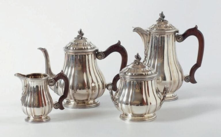 SERVICE QUATRE PIÈCES en argent composé d'une théière, une cafetière, un sucrier couvert et un pot à lait à piédouches, les corps à côtes rondes, les prises en fleur éclose, les anses en bois bru