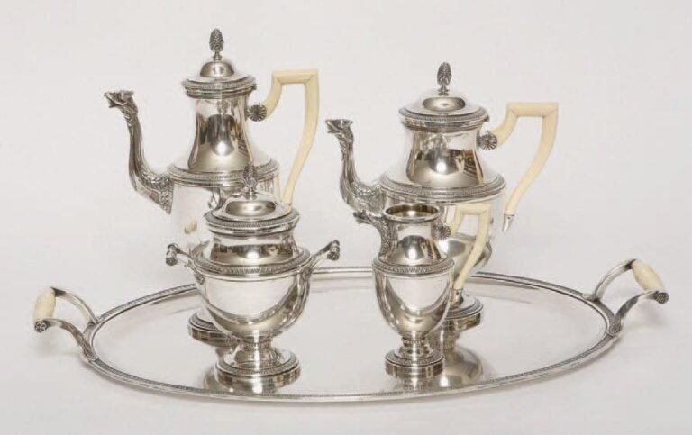 Service quatre pièces en argent composé de deux théières, un sucrier couvert et un crémier et son plateau en métal argenté, toutes les pièces à frises de feuilles d'eau, les becs verseurs en têtes d'aigle, les anses en ivoire (fêles