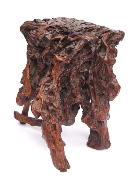 Socle en bois confectionné à partir d’une racine de couleur marron-rouge et de forme irrégulièr