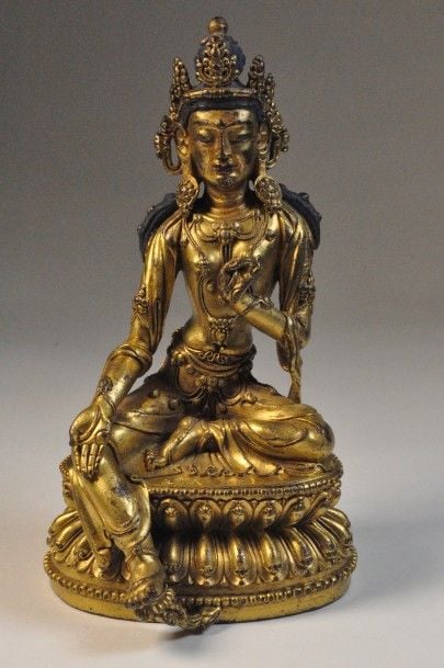 Statuette en bronze doré représentant tara verte, assise en Lalitasana, la main gauche en Kartari mudra et la droite en varada mudra, vêtue d’un dhoti, et parée de bijoux assise sur un socle à décor de lotu