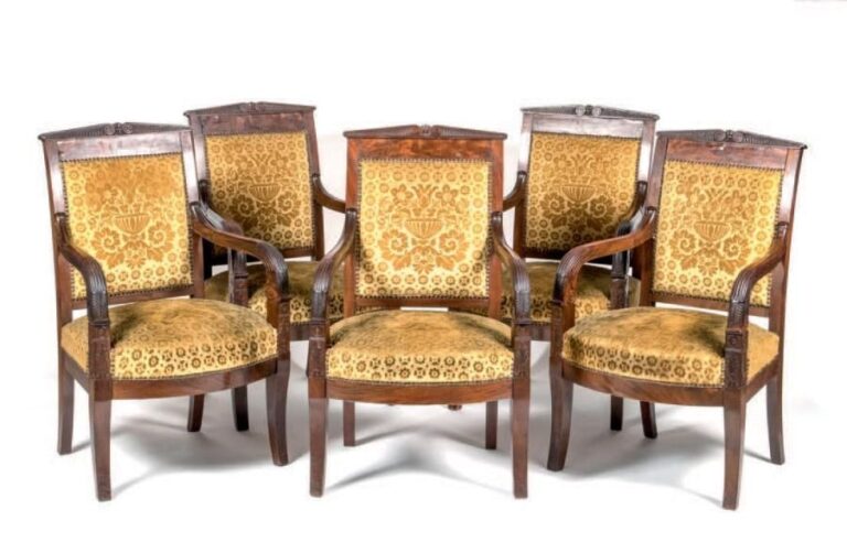 Suite de cinq fauteuils en acajou et placage d'acajou; les dossiers légèrement incurvés sommés de motifs et feuillages stylisés; accotoirs sinueux; pieds sabre