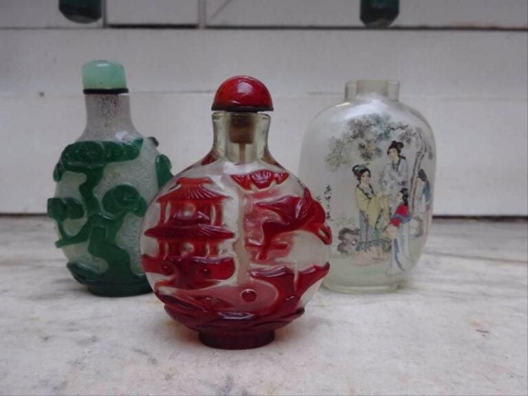 SUITE DE DEUX FLACONS TABATIERES OVOIDES EN VERRE OVERLAY DE BEIJING / PEKIN Chine, Epoque XXe siècle Le premier dans les tons verts à décor de bambous ; le second dans les tons rouges orné d'une carpe jaillisant hors des flots et de la bouche de laquelle sortent des volutes nuageuses sommées d'un pavillon, dans le ciel une grue tenant dans son bec un lingzhi et une chauve-souri