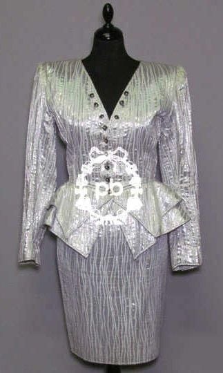 TAILLEUR du SOIR en lamé argent zébré, veste cintrée à encolure en pointe sur simple boutonnage 'coquillage' rehaussé d'une perle, rappel aux poignets, effet de double basque formant petits godets, jupe droite ornée d'un noeud dans le dos (env T38) (petite salissure)