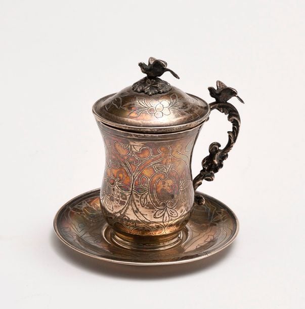 TASSE COUVERTE et sa SOUCOUPE en argent gravé de décor de fleurs, le couvercle et la anse à décor rocaille surmontés d'une colomb