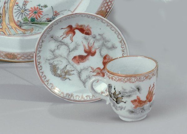 Tasse et sous tasse en porcelaine blanche décorée en émaux polychromes de cyprins nageant parmi les algue