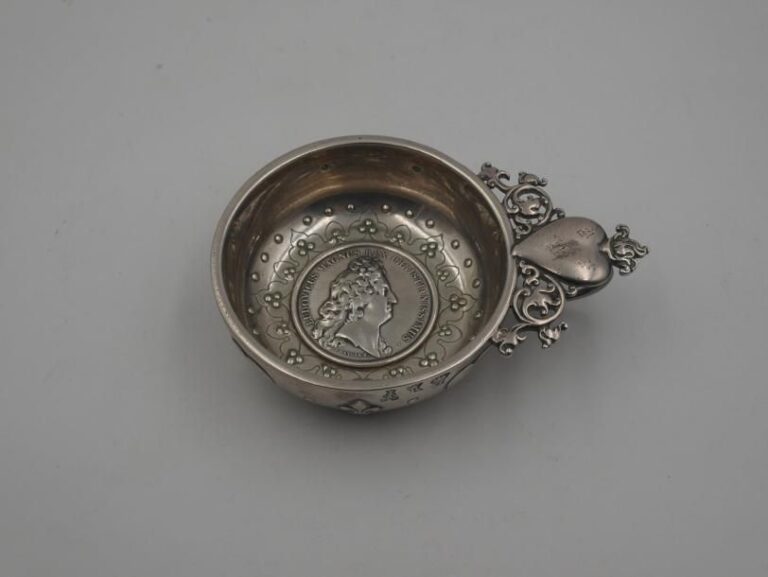 Taste-vin en argent (950 millièmes), le fond à décor d'une médaille "Ludovicus Magnus), l'aappui-pouce à ceour ardent et entrelac feuillag