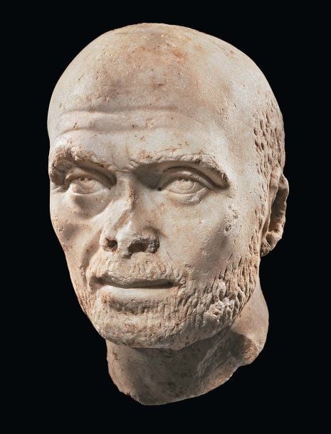 TÊTE MASCULINE Tête en marbre blanc, représentant un homme d'âge mûr, au visage ovale, la chevelure et la barbe courtes, les sourcils épais, son large front dégarni creusé de deux plis, le nez droit, la bouche charnue sous une courte moustach