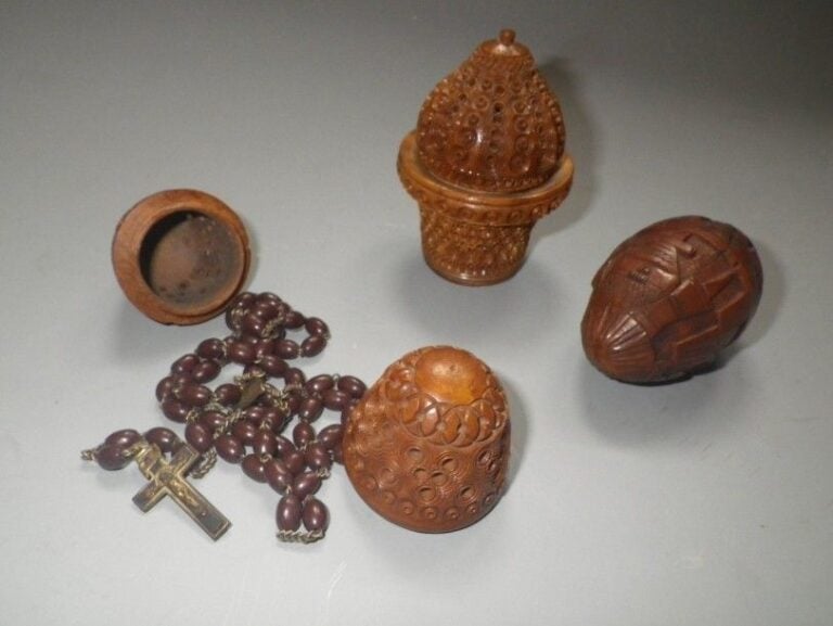 Trois boîtes en corozo en forme d'oeufs ou de panier, sculptés ou repercés et contenant chacune un chapelet Les trois