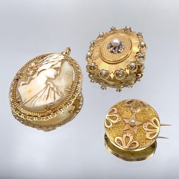 •Trois BROCHES en or jaune (750‰) circulaire et ovale, orné de perles de culture et diamants taillés en rose et un camée coquill