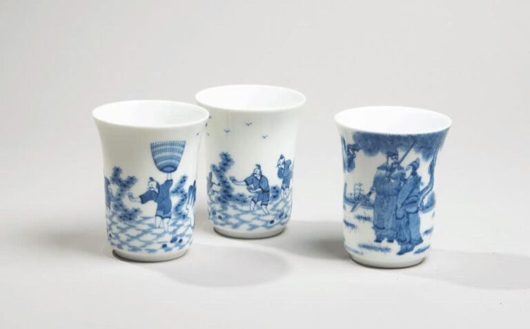 Trois gobelets en porcelaine à décor en bleu sous couverte de pêcheurs et de dignitaires sur l'un