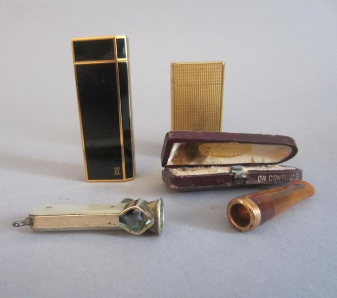Un ensemble comprenant : briquet Cartier, briquet métal doré guilloché, fume-cigarette en ambre monté or (750 millièmes) (poids brut :