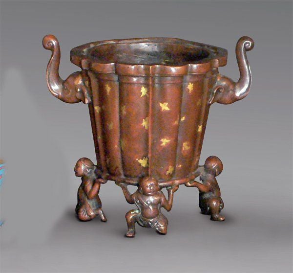 Vase en bronze de patine brun clair à décor « gilt-splashed », à parois droites godronnées et bords lobées, porté par quatre personnages formant pied