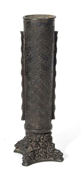 Vase en bronze foncé en forme de pilier rond avec des nervures dentelées sur deux côtés et décoré d'un relief en méandre (manjitsunagi) reposant sur une base carré