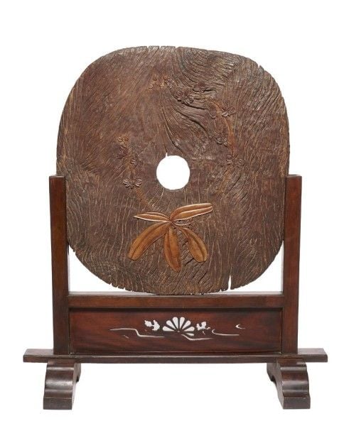 Vieille roue en bois massif érodé décorée d'incrustation en bois clair représentant une fleur d'orchidé