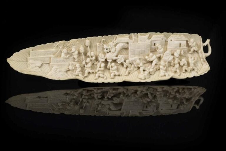 [X] CHARMANTE FEUILLE DE BANANIER EN IVOIRE SCULPTE Chine, Fin de la Dynastie Qing, Epoque fin du XIXe siècle Elle est sculptée sur ses deux faces, sur l'avers d'une procession d'enfants saisis dans la fête du dragon / nouvel an, au revers les nervures de la feuill
