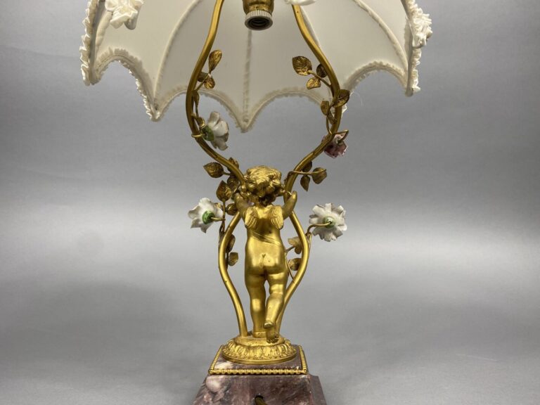 Pied de lampe en bronze doré soutenu par un angelot et ponctué de fleurettes en…