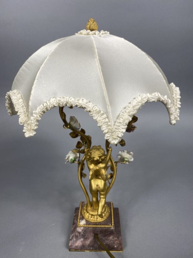 Pied de lampe en bronze doré soutenu par un angelot et ponctué de fleurettes en…